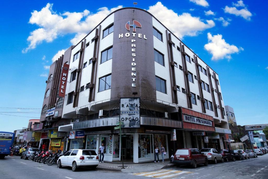 Hotel Presidente Ipatinga في إيباتينجا: مبنى الفندق على شارع المدينة بسيارات متوقفة