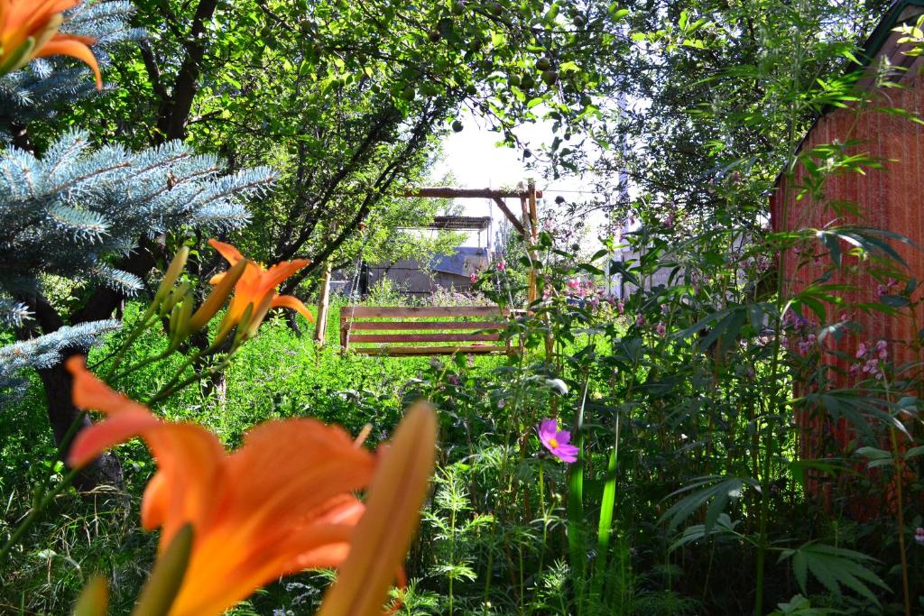 um jardim com um banco ao fundo com flores em Serik & Geora Guesthouse em Sevan