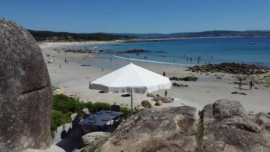 plaża z białym parasolem i ludźmi w wodzie w obiekcie Apartamentos Luis Antonio Mestre w mieście O Grove