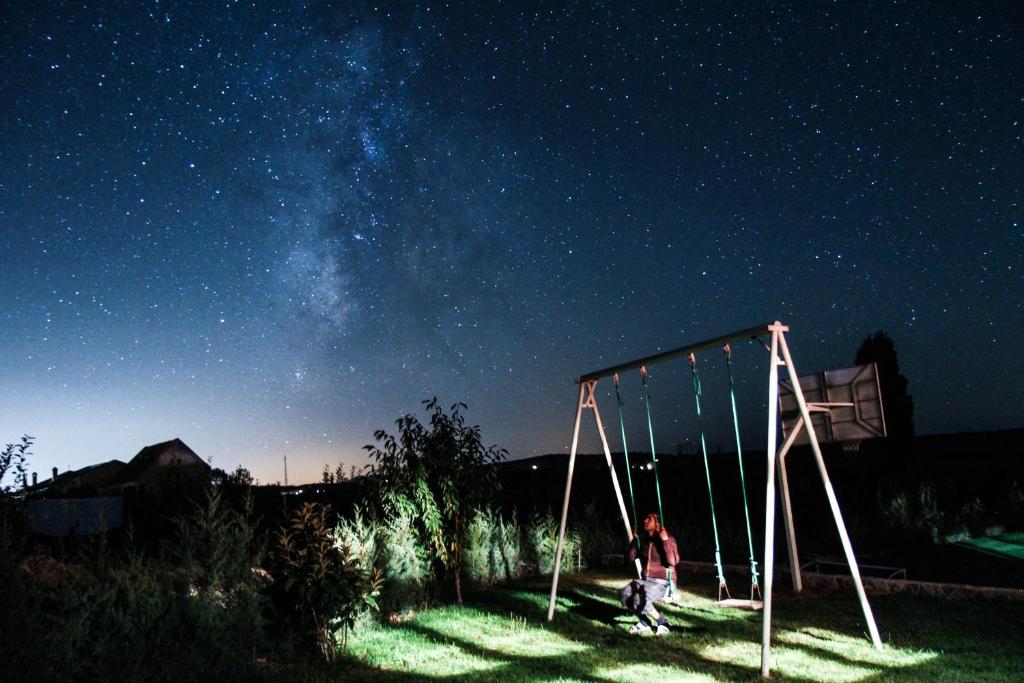 a man is sitting on a swing at night at La pommeraie d'Ifrane in Ifrane