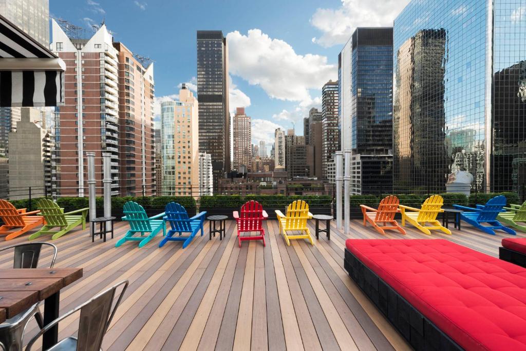 une terrasse avec des chaises et des tables colorées dans une ville dans l'établissement Pod 51, à New York