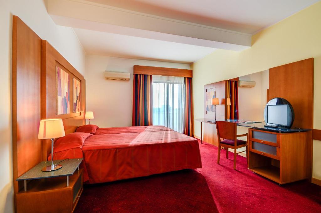 a hotel room with a bed and a desk and a television at Hotel Alvorada in Estoril