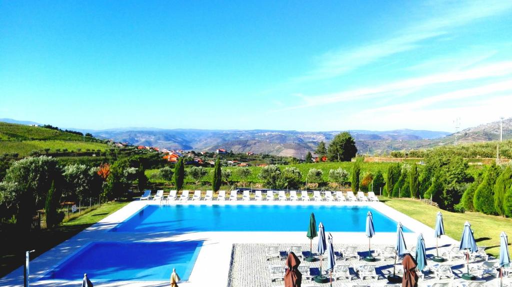 a large swimming pool with chairs and umbrellas at Quinta do Atoleiro in Lamego