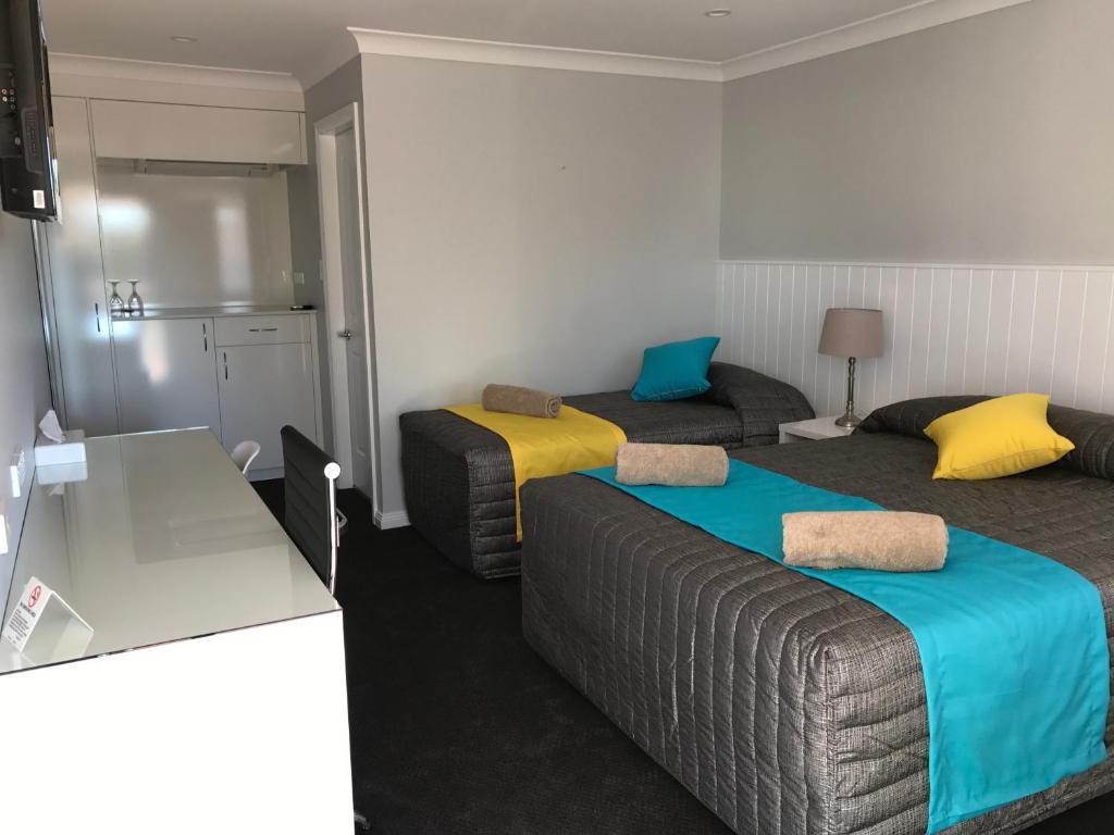 a hotel room with two beds and a kitchen at Oasis Motel in Cobar