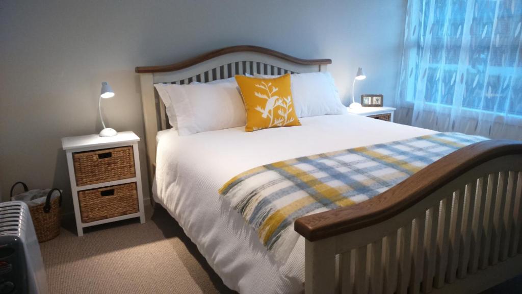 a bedroom with a bed with a yellow pillow and two lamps at Restview in Dunedin