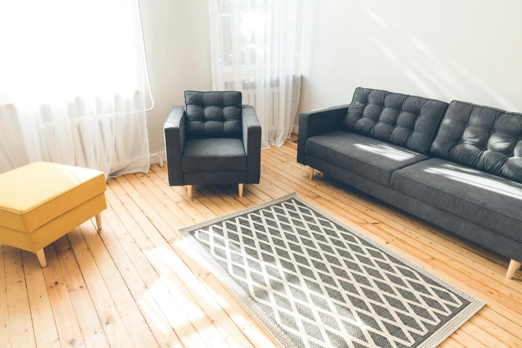 a living room with a black couch and a chair at Krastmala in Liepāja