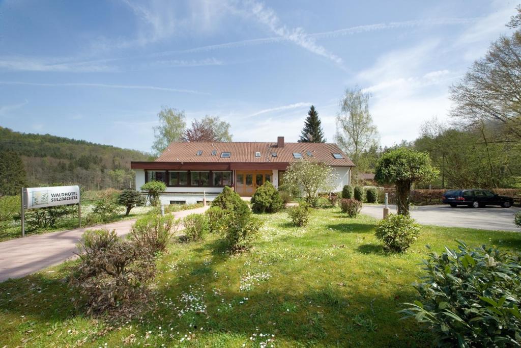 una casa con un jardín delante de ella en Waldhotel Sulzbachtal, en Schönaich