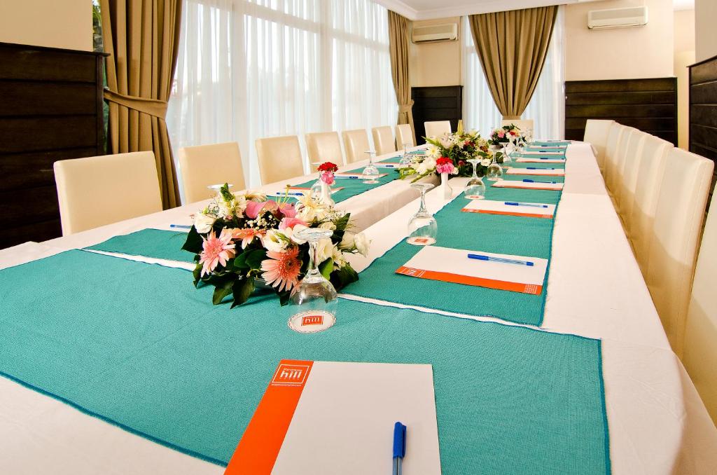 a long table with green and white tables and flowers at City's Hill Hotel in Kuşadası