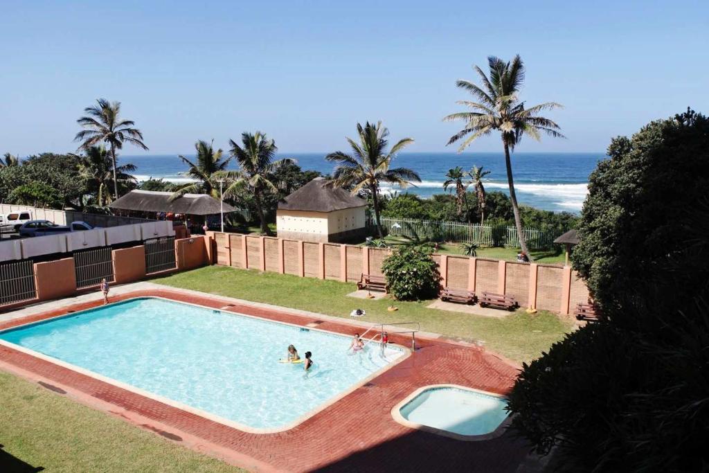 - une piscine avec des personnes et l'océan en arrière-plan dans l'établissement Silver Dolphin Holidays, à Amanzimtoti