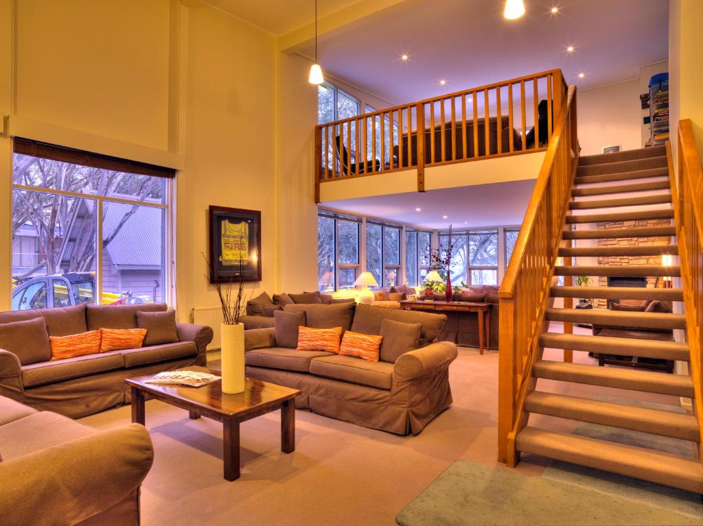a living room with a staircase and a couch at Ajax Ski Club in Mount Buller