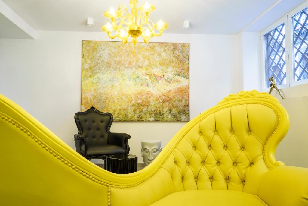 un sofá amarillo en una sala de estar con una pintura en The Walt Madrid, en Madrid
