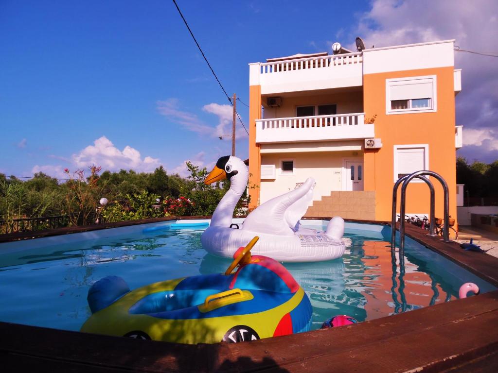 two swans and a toy boat in a swimming pool at Kouros Chania Villas in Maleme