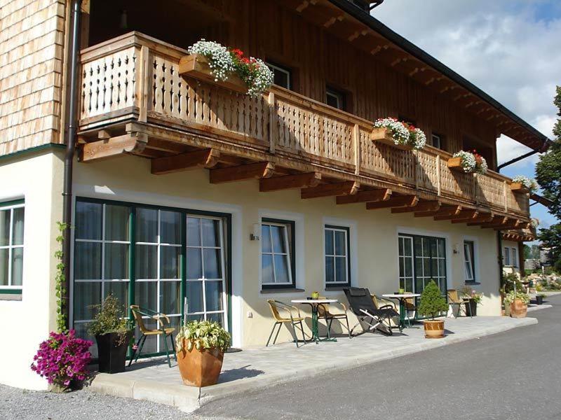 a building with a balcony and a table and chairs at Appartements Stiererhof in Ramsau am Dachstein