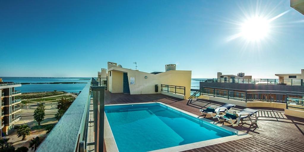 a swimming pool on top of a building with the ocean at Pilot House - Village Marina in Olhão
