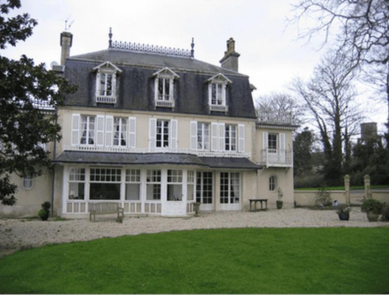 une grande maison blanche avec un banc dans une cour dans l'établissement Chambres d'Hôtes Le Petit Sully, à Sully