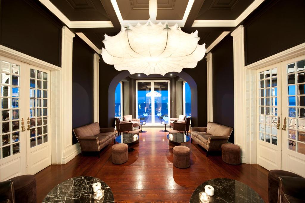 a large living room with a chandelier and chairs and tables at Farol Hotel in Cascais
