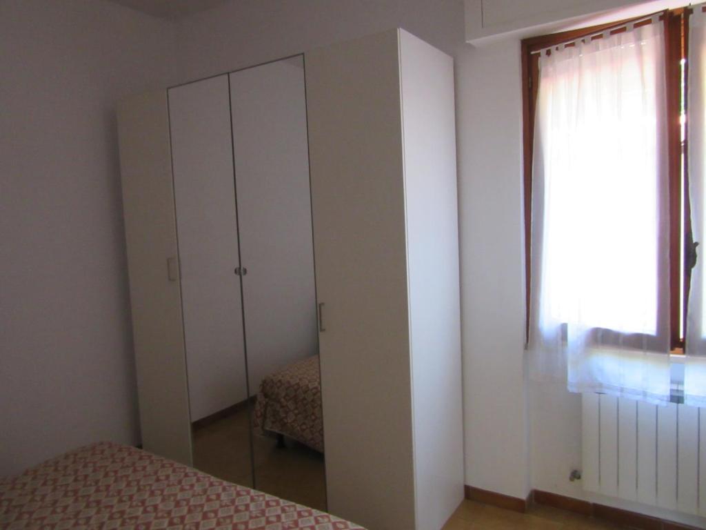 UscioにあるGaraventa Angelo Apartmentsのベッドルーム1室(ベッド2台、クローゼット、窓付)