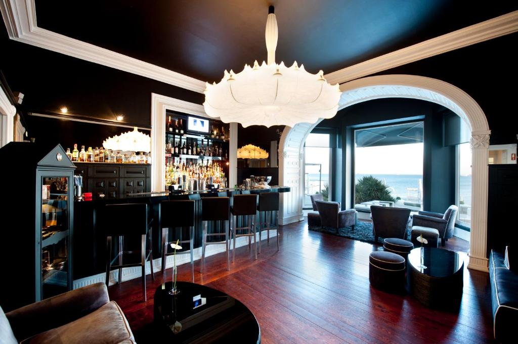 a bar with black walls and a chandelier at Farol Hotel in Cascais