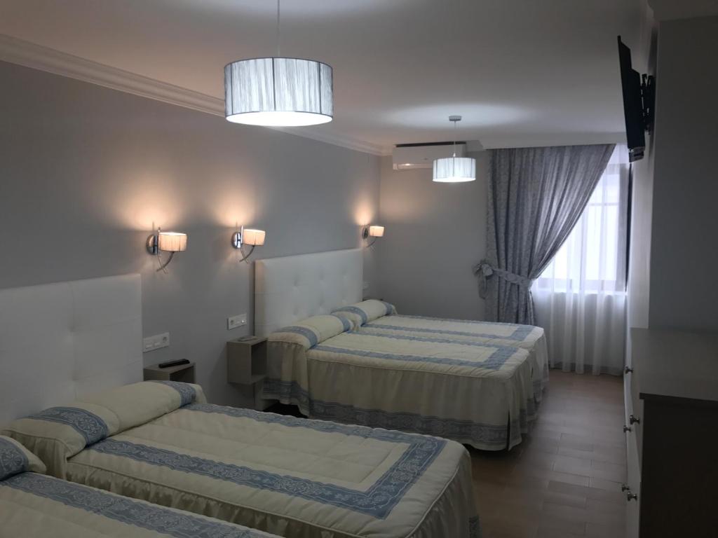 a hotel room with three beds and a window at Hotel Plaza Damasco in Almuñécar