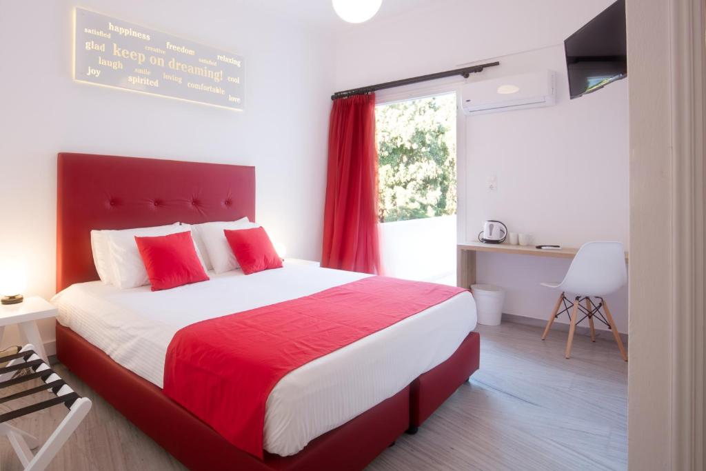 Un dormitorio con una cama roja y blanca y una ventana en Acqua Vatos Paros Hotel, en Parikia