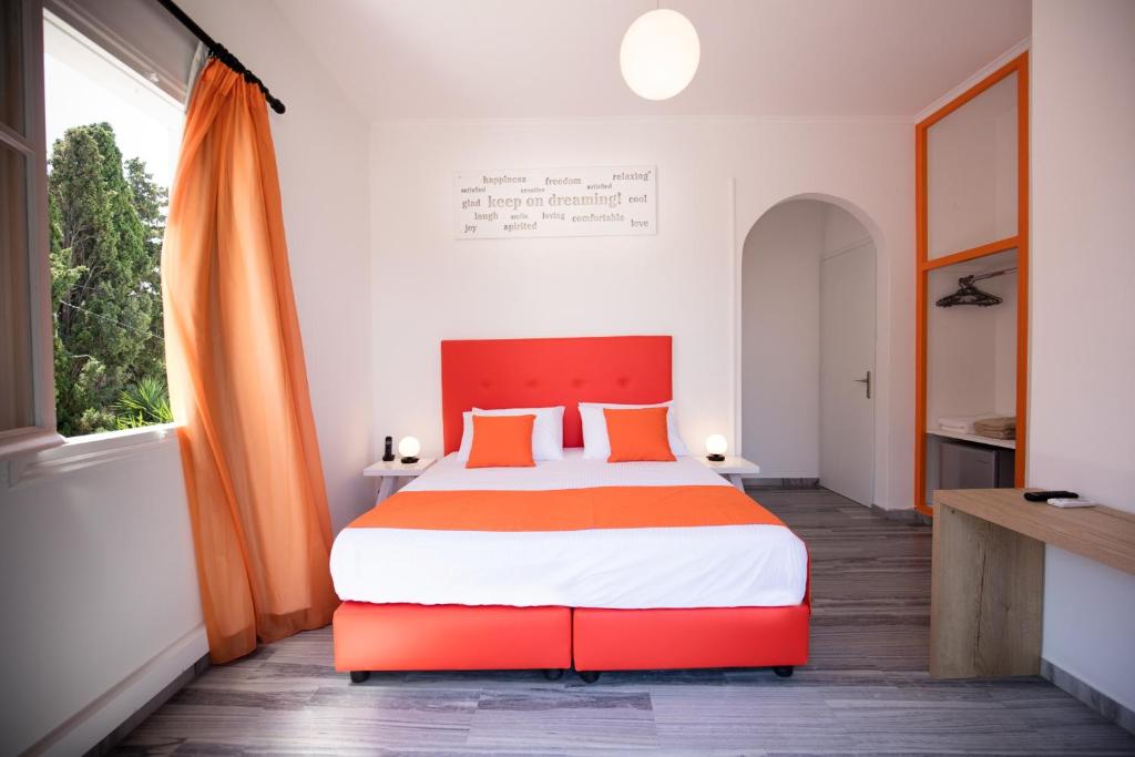 sypialnia z dużym łóżkiem z pomarańczową i białą pościelą w obiekcie Acqua Vatos Paros Hotel w mieście Parikia