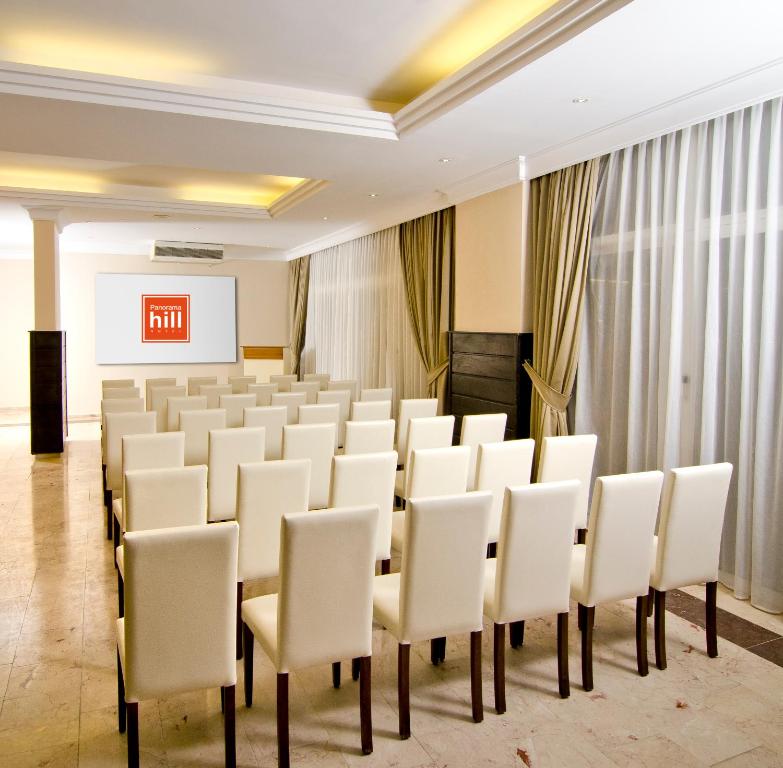 a conference room with white chairs and a screen at City's Hill Hotel in Kuşadası