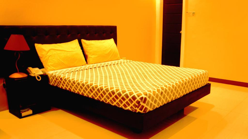 Urbantel Hotel في لوسينا: غرفة نوم مع سرير بجدران صفراء ومصباح