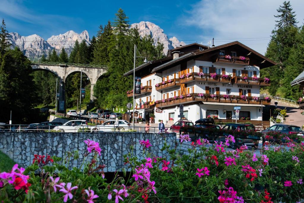 Un edificio con un mazzo di fiori davanti di Meuble Villa Neve a Cortina dʼAmpezzo