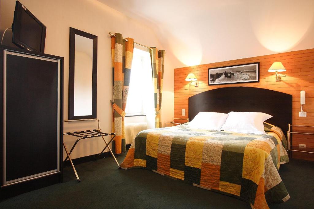 a hotel room with a bed and a flat screen tv at L'Armoric Hôtel in Bénodet