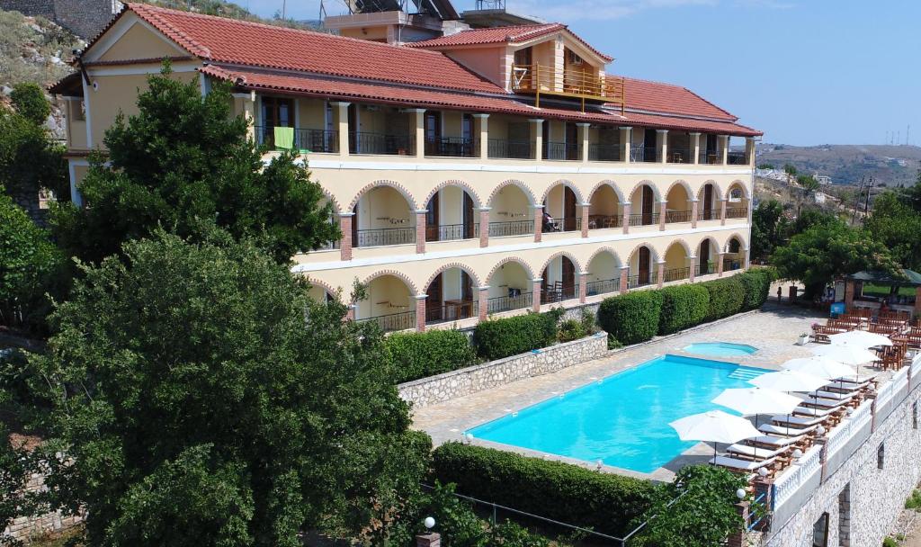 a large building with a swimming pool in front of it at Apart-Hotel Llazari in Himare