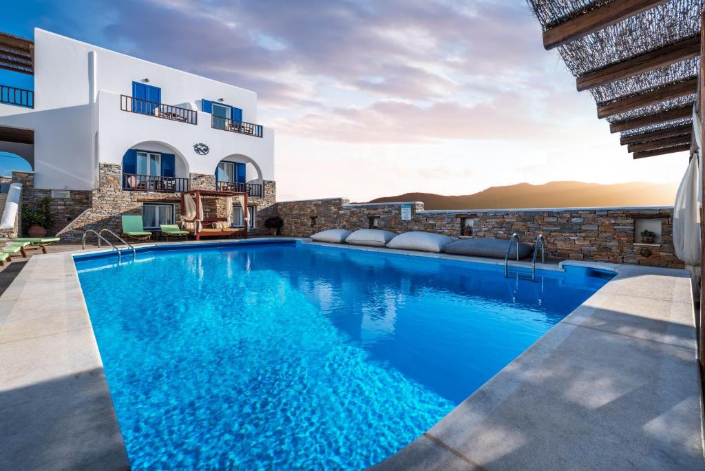 a villa with a swimming pool in front of a building at Ios Resort in Ios Chora