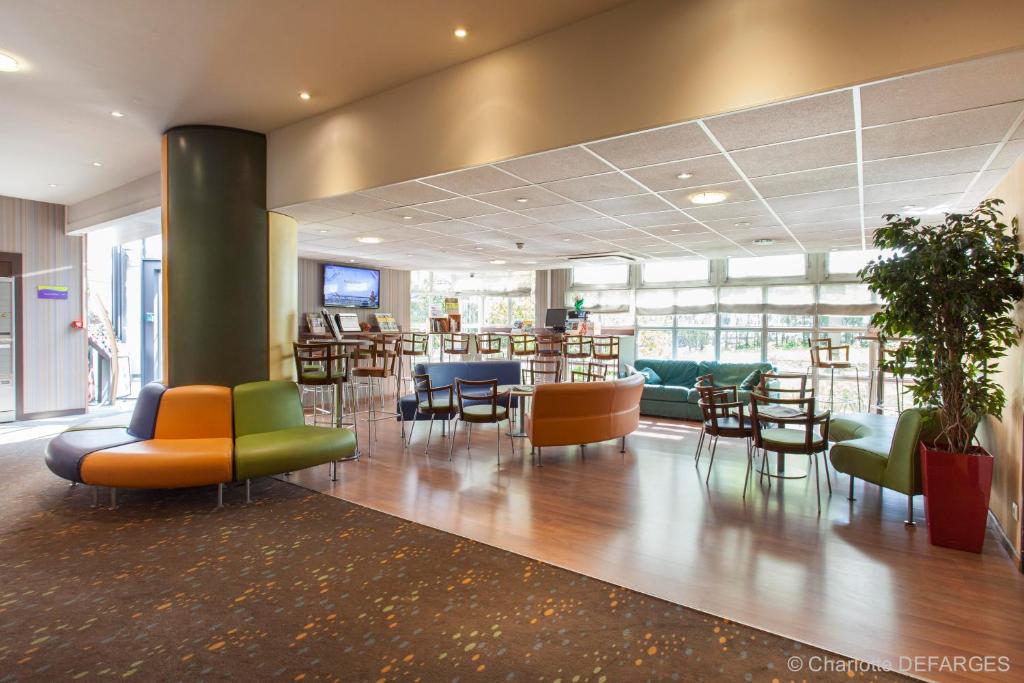 a lobby with a waiting area with chairs and tables at Canal Suites by Popinns in Pantin