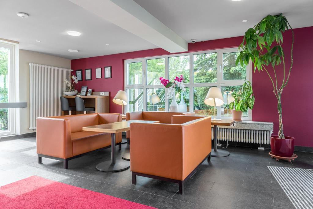 comedor con sillas de color naranja y paredes púrpuras en Serways Hotel Heiligenroth, en Montabaur