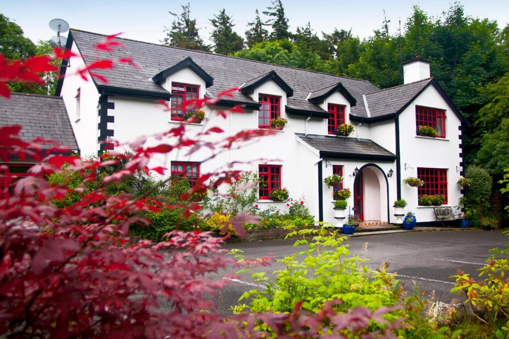 a white house with red windows and flowers at Woodside Lodge accomodation in Westport