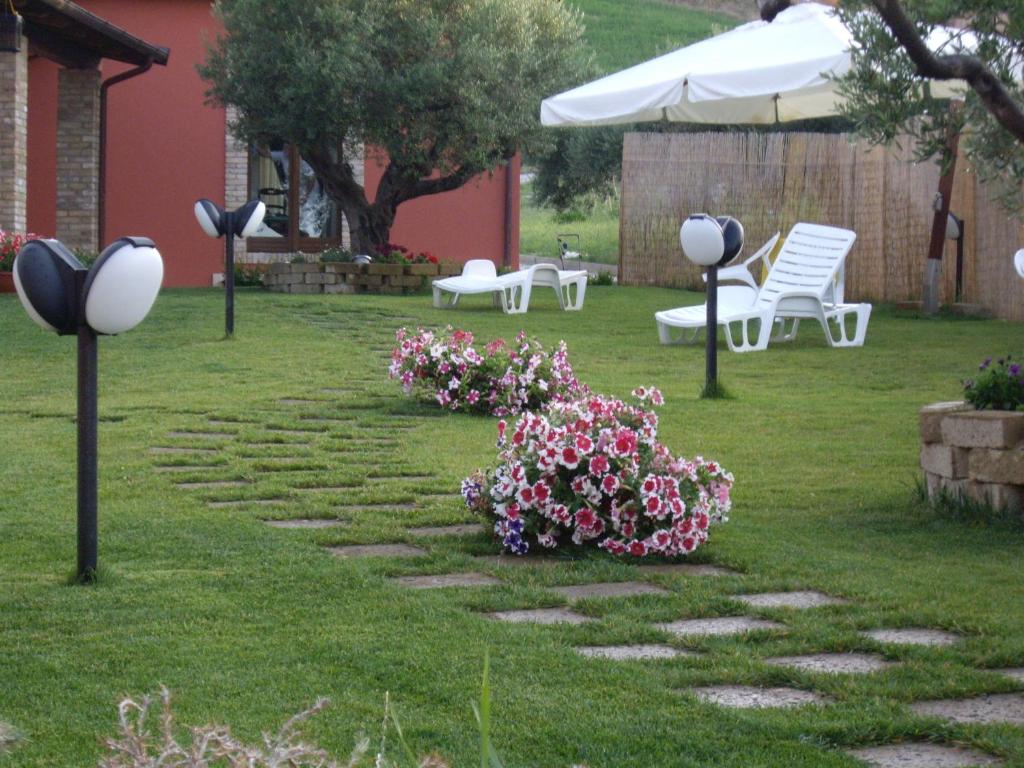 un jardín con sillas blancas y flores en la hierba en Agriturismo Il Borgo Degli Ulivi, en Roseto degli Abruzzi