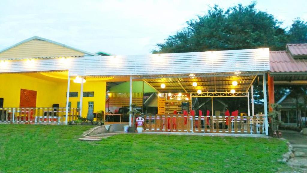 a yellow house with a patio with tables and chairs at Ban Tonnam Resort in Suan Phung