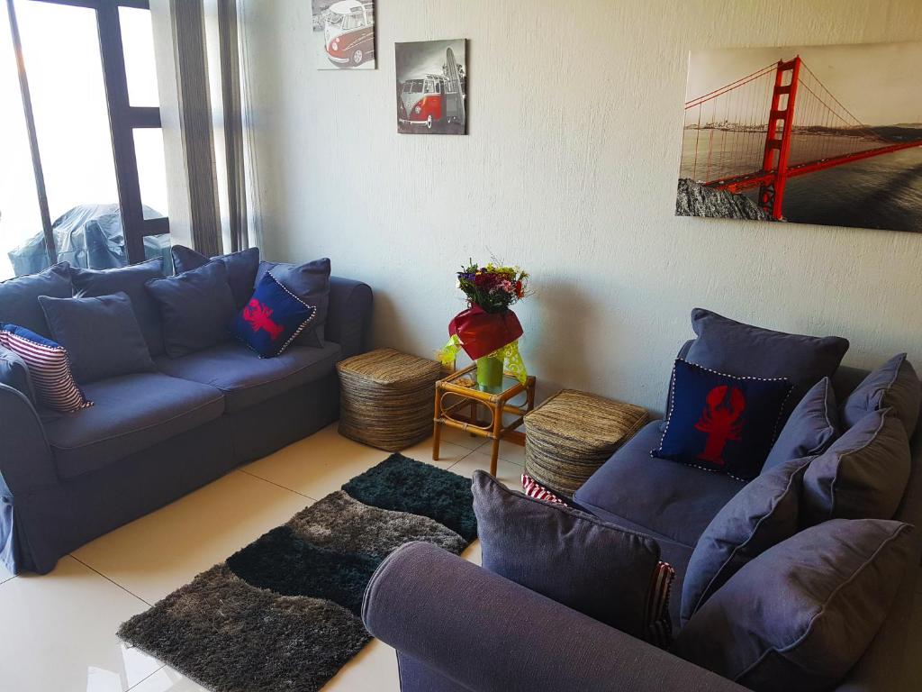 a living room with blue couches and a red bridge at Dumela Margate Flat No 17 in Margate