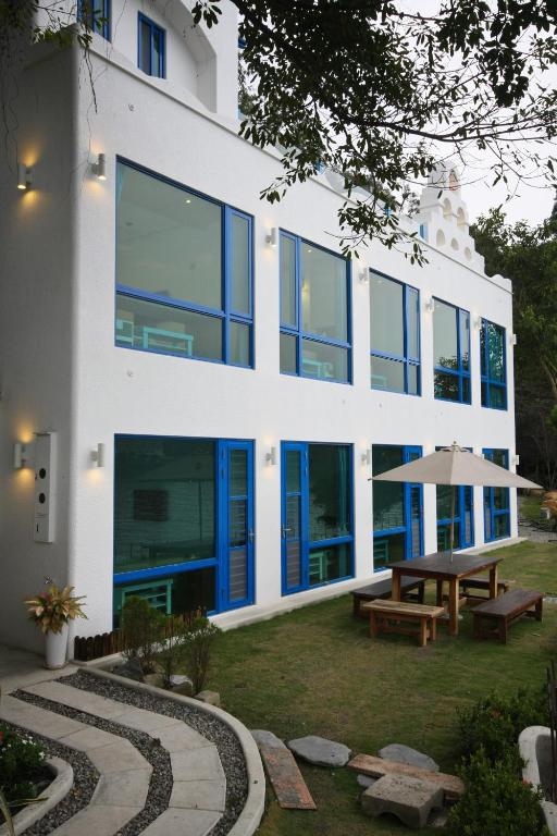 a white building with blue windows and a picnic table at Sun Fog Hotel in Yuchi