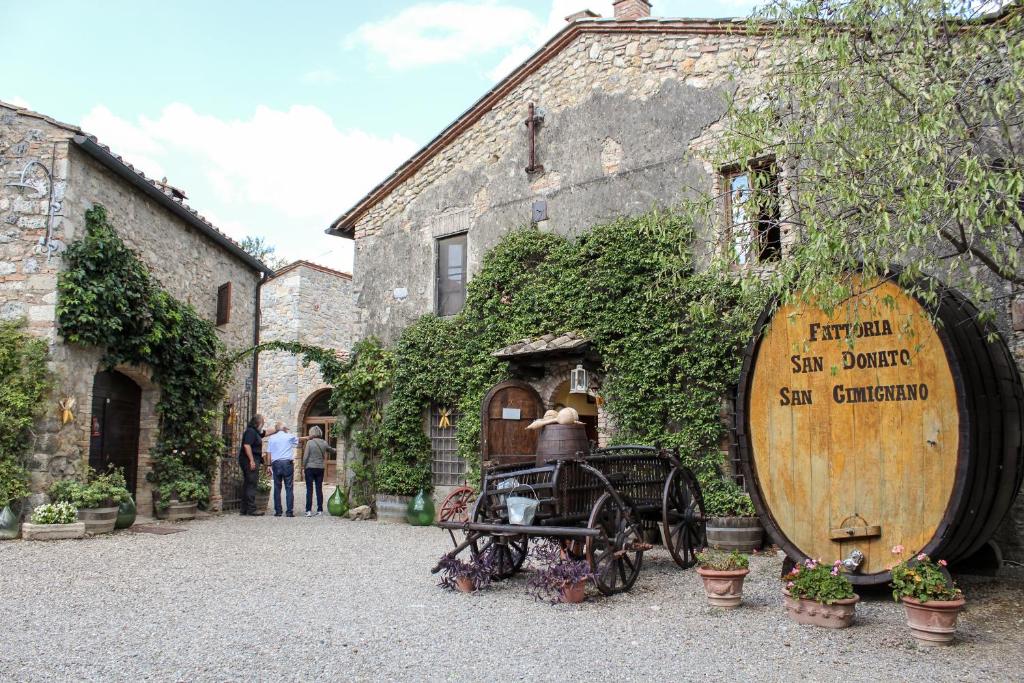 duża drewniana beczka wina obok budynku w obiekcie Fattoria San Donato w mieście San Gimignano