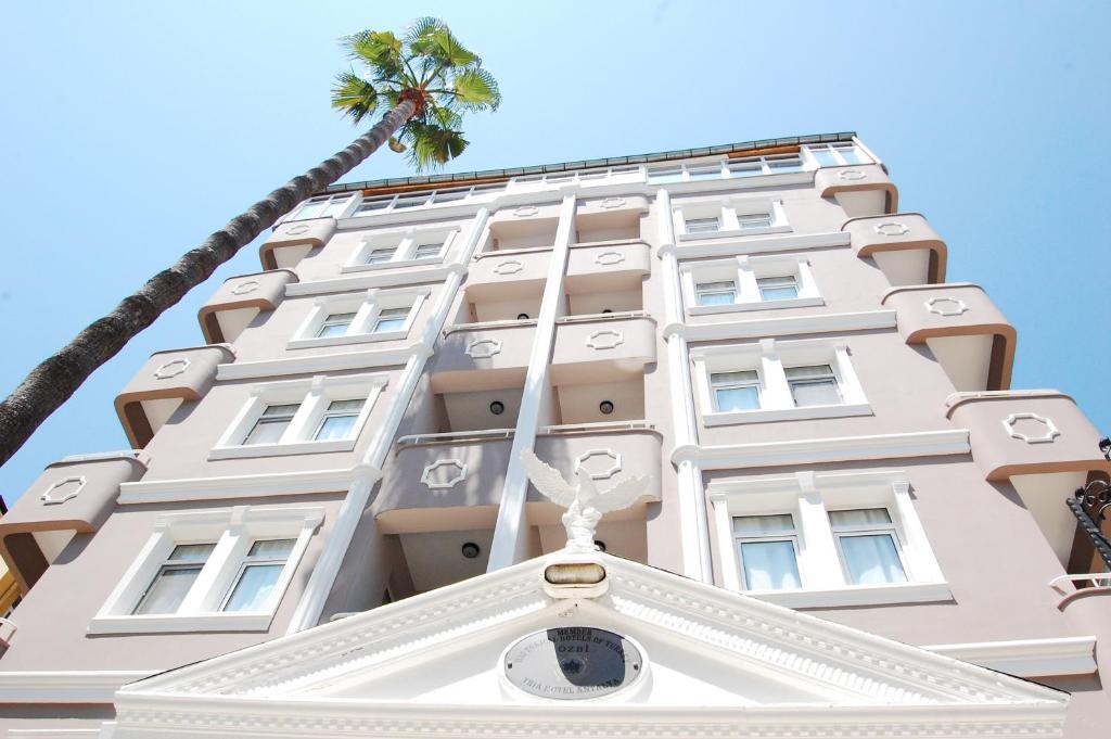 a tall white building with a palm tree at Triana Hotel in Antalya
