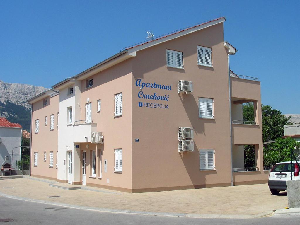 a building with a sign on the side of it at Apartments Crneković V in Baška