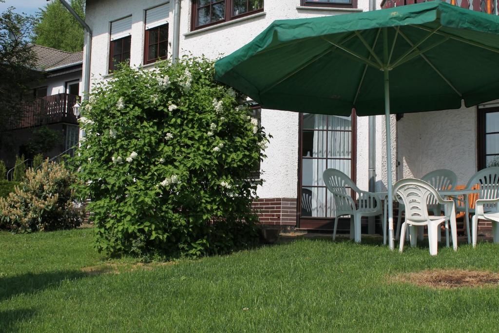 a table and chairs under an umbrella on a yard at Ferienwohnung Waldschlößchen in Wattenbach