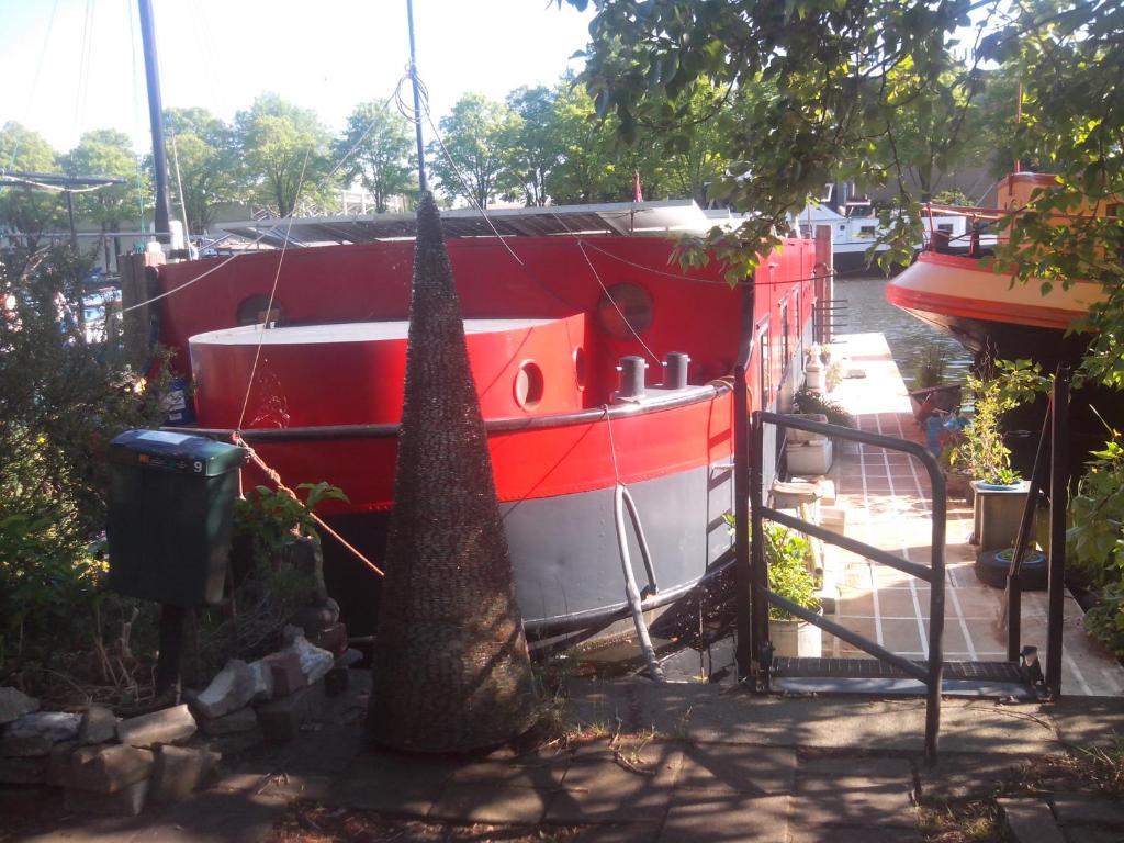 a red and white boat parked next to a tree at Houseboat Dokstroom in Amsterdam