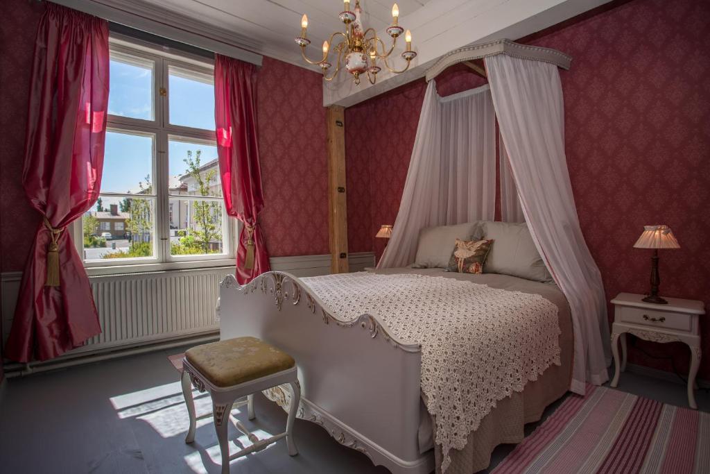 a bedroom with a canopy bed and red walls at Boutique Hotel Langin Kauppahuone in Raahe
