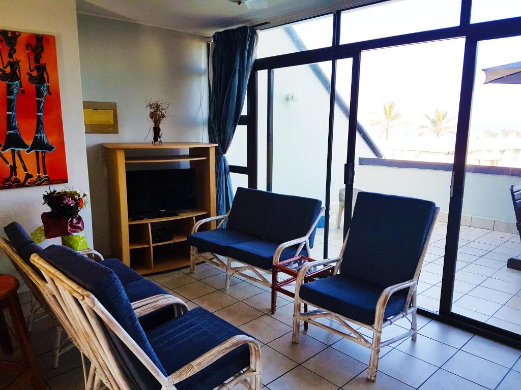 uma sala de estar com três cadeiras e uma televisão em Dumela Margate Flat No 30 em Margate