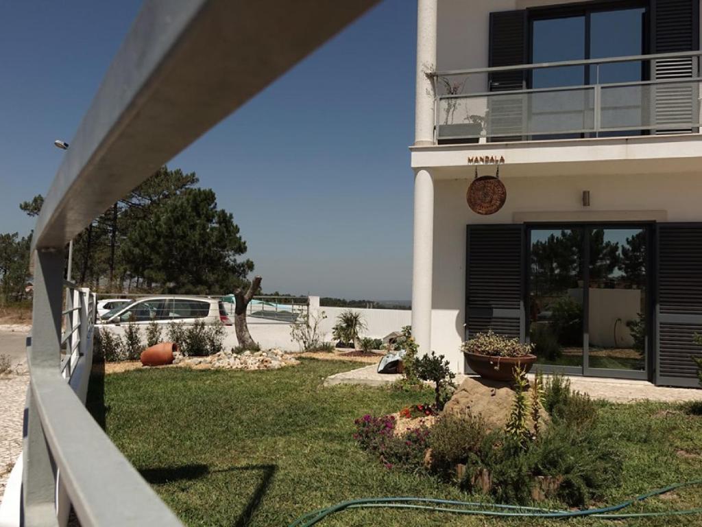 a house with a hose in front of a yard at Mandala House Sesimbra in Cotovia