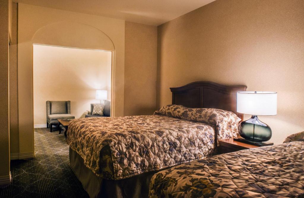 a hotel room with two beds and a chair at Inn on Barons Creek in Fredericksburg
