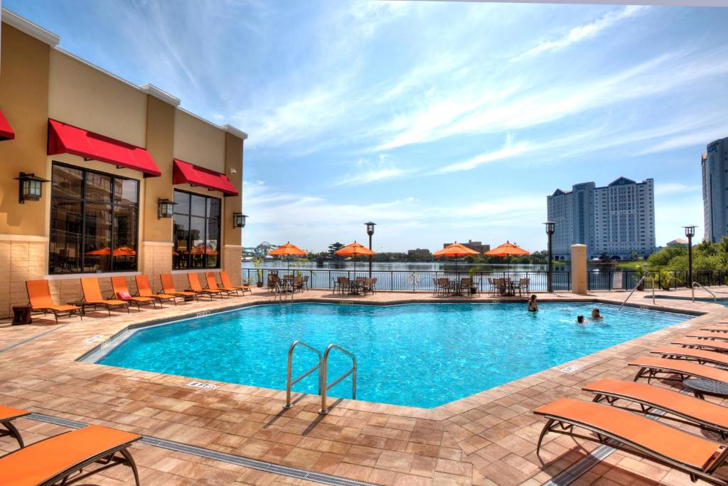 uma piscina num hotel com cadeiras e pessoas em Ramada Plaza by Wyndham Orlando Resort & Suites Intl Drive em Orlando