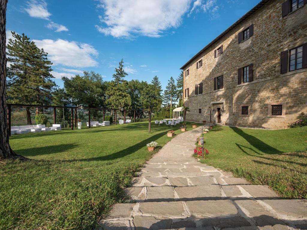 un edificio in pietra con un sentiero accanto a un prato di Hotel Villa Montegranelli a Gubbio