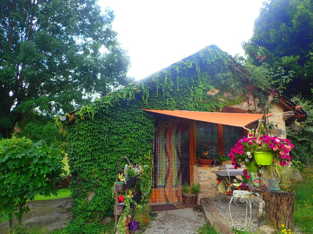 une petite maison avec un toit orange et des fleurs dans l'établissement Mas de La Boheme - L'Hermet, à Saint-Léons